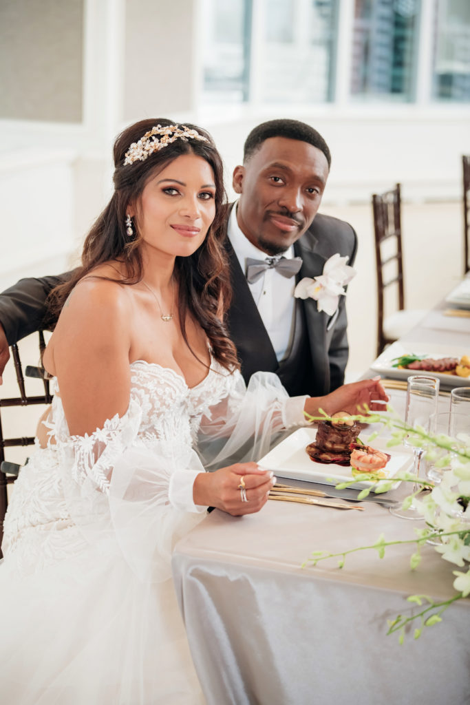 Bride and groom sitting at a table with food  | Weddings & Events by Cheryl Munro | Toronto Wedding Planner