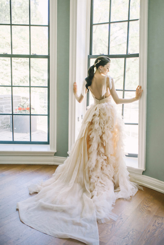 Bride in ruffled dress looking out window  | Weddings & Events by Cheryl Munro | Toronto Wedding Planner