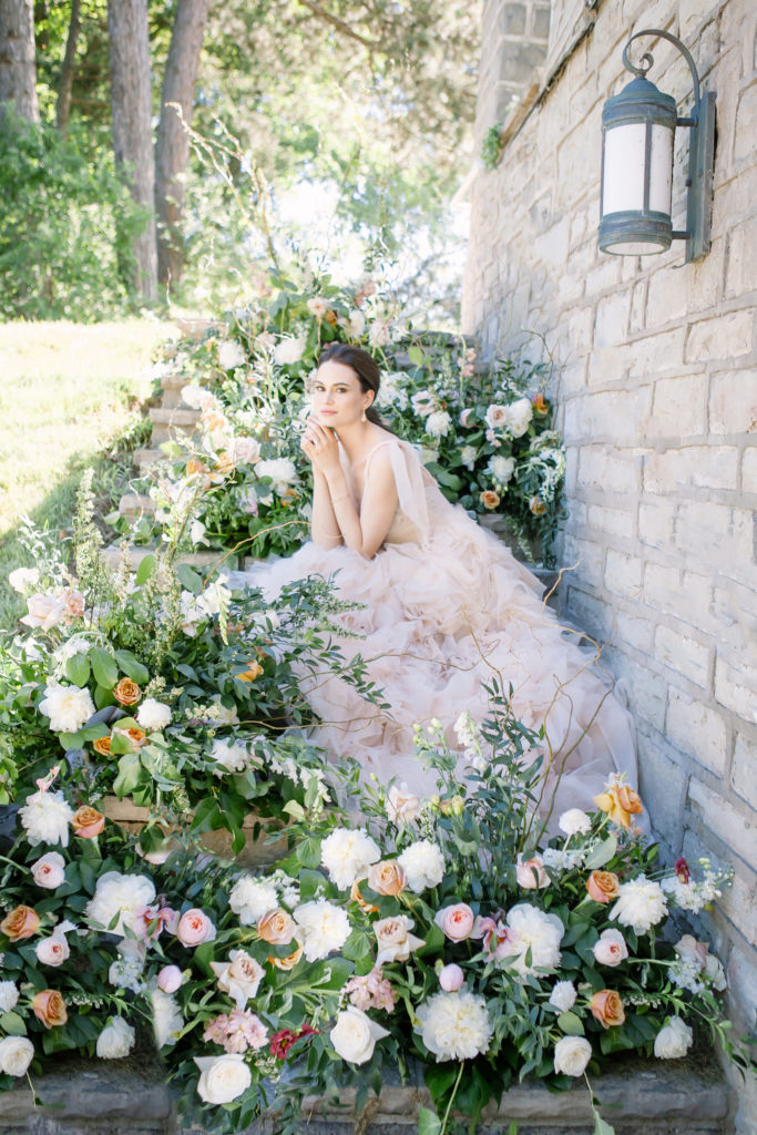 Bride sitting on stairs surrounded by flowers  | Weddings & Events by Cheryl Munro | Toronto Wedding Planner