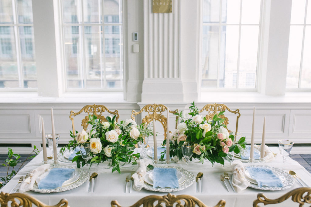 Table with a vintage white charger plate with a blue fabric menu and gold cutlery with flowers | Weddings & Events by Cheryl Munro | Toronto Wedding Planner