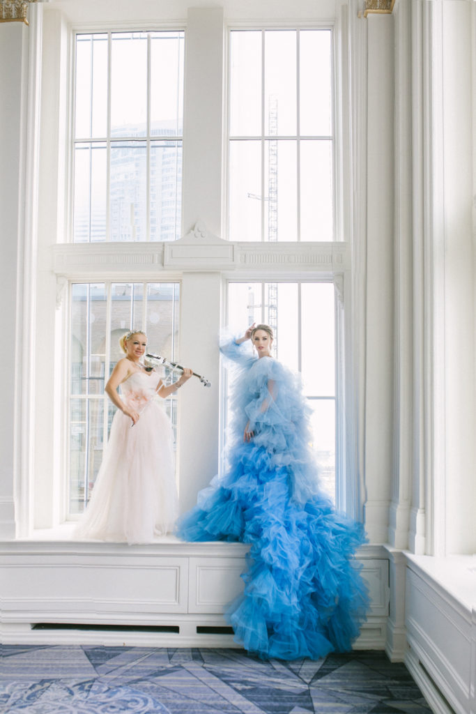Bride in blue ruffle dress and violist standing in large white floor to ceiling windows  | Weddings & Events by Cheryl Munro | Toronto Wedding Planner