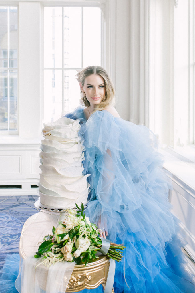 Bride in blue ruffle dress standing beside a ruffled white wedding cake  | Weddings & Events by Cheryl Munro | Toronto Wedding Planner
