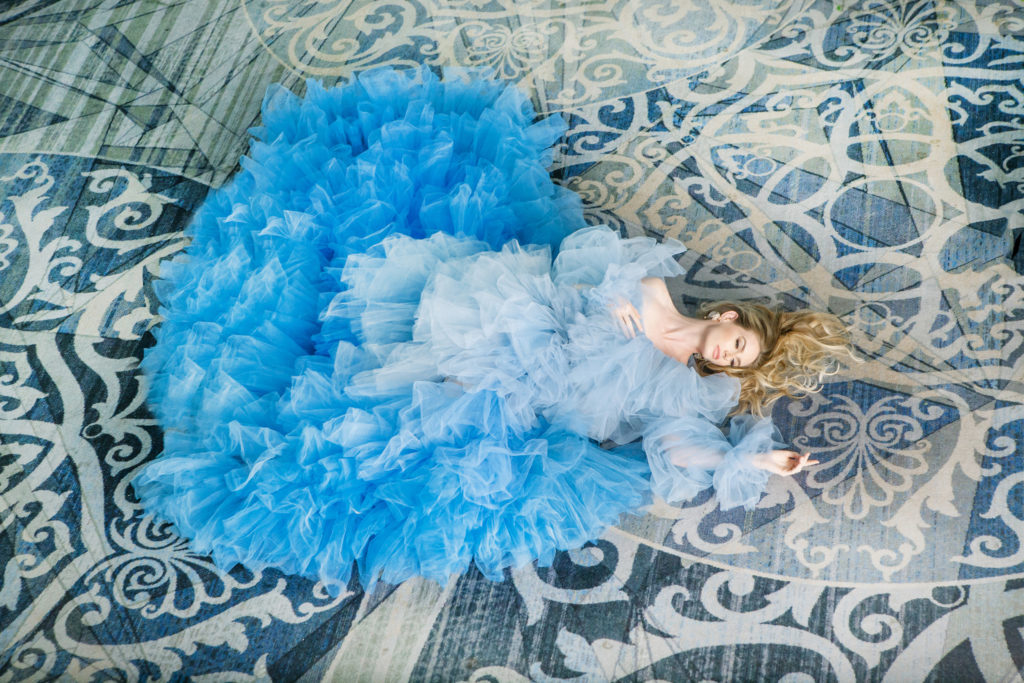 Bride in blue ruffle dress laying on blue pattern carpet  | Weddings & Events by Cheryl Munro | Toronto Wedding Planner