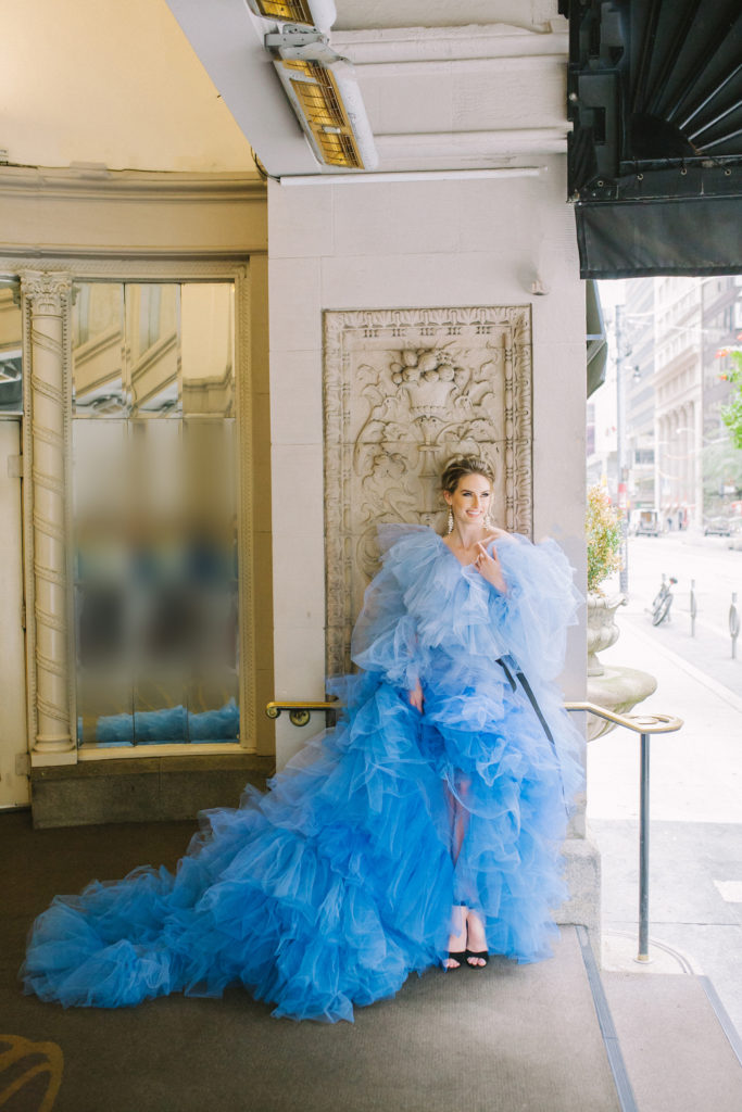 Bride in blue ruffle dress standing in front of the King Edward Omni Hotel   | Weddings & Events by Cheryl Munro | Toronto Wedding Planner